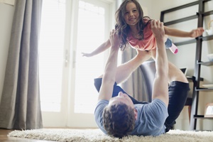 床に寝転んで遊ぶ親子の画像